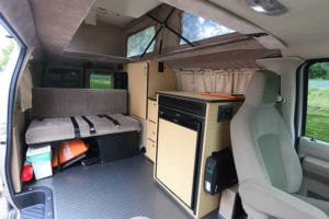 Inside 4wd Ford Econoline adventure van conversion with kitchen and sofa bed