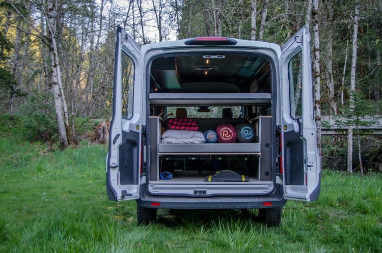 Looking inside the rear doors of a Ford Transit Campervan with beds and storage built by Axis Vehicle Outfitters in Portland, Oregon