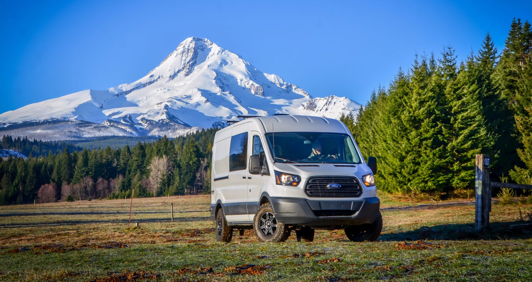 Exterior shot of front side of Ford Transit Campervan with Mt. Hood in background built by Axis Vehicle Outfitters in Portland, Oregon