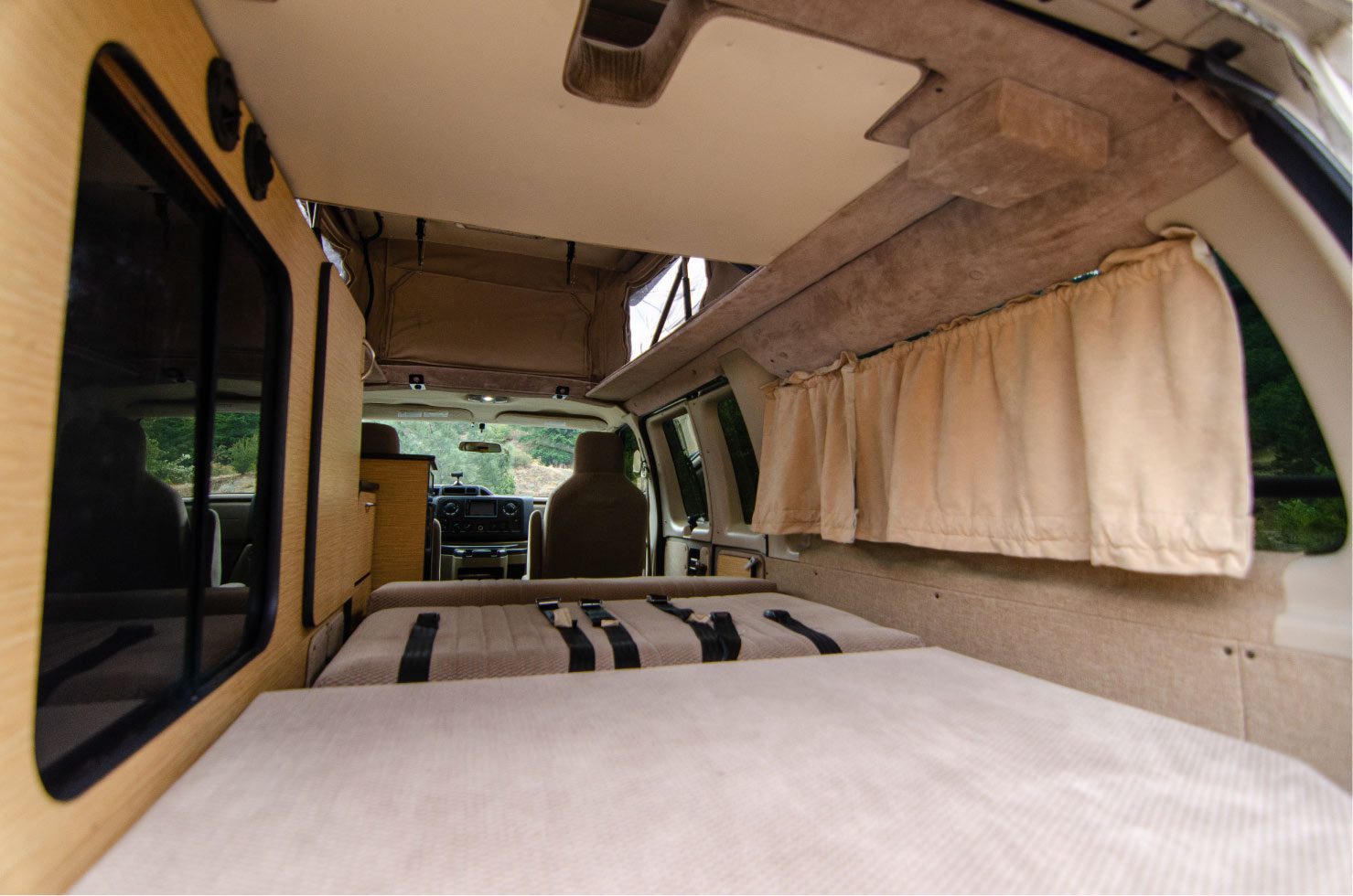 Inside view of the lower bed and sofa bed in a Ford E-Series 4x4 Econoline Sportsmobile RB50 Layout Campervan conversion for sale built by Van Specialties